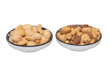 Nuts background. Close-up of roasted and salted macadamias, almonds, cashew nuts in two ceramic bowls isolated on a white background. Gourmet nut mix with macadamias. Macro.