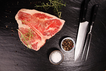 Raw T-bone steak on stone cutting board.
