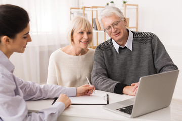 Obraz premium Older couple considering new home purchase looking at laptop