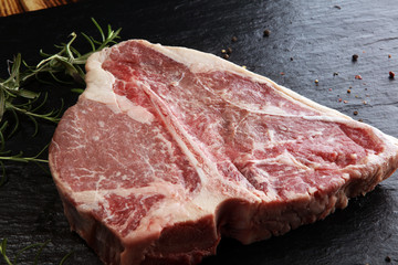 Raw T-bone steak on stone cutting board.