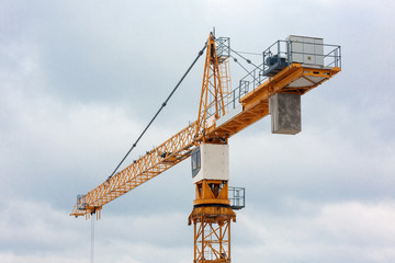 Fragment of a tower crane with a cabin on a background of blue sky.