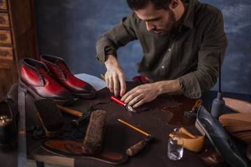 pleasant man preparing leather accessories for clients. close up photo