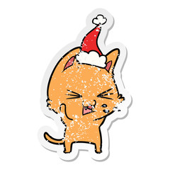 distressed sticker cartoon of a cat hissing wearing santa hat