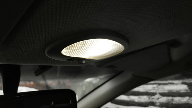 Close Up photo light on in car salon. Open hand lamp in car.
