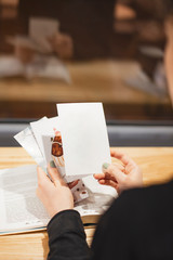 girl looking at greeting cards sitting at a cafe table. selective focus, noise effect, copy space