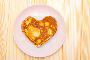 Heart shaped pancakes for romantic breakfast. Shrovetide (carnival) concept. On wooden background, top view