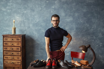 cheerful stylish shoemaker with hand on his hip posing to the camera. close up photo