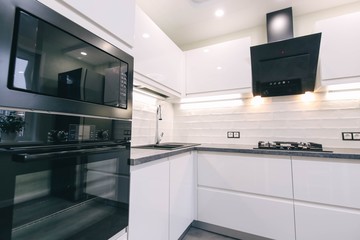 modern white kitchen interior with   LED backlight. Household appliances oven, gas stove, hood.