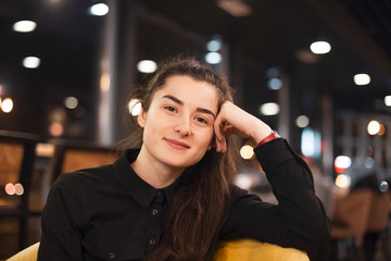 young attractive brunette is having fun at the cafe, smiling and posing for the photo in the evening. selective focus, noise effect