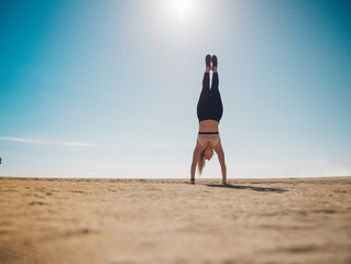 woman wearing sport wear doing a hanstand