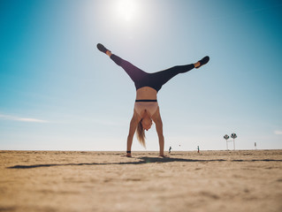 woman wearing sport wear doing a hanstand