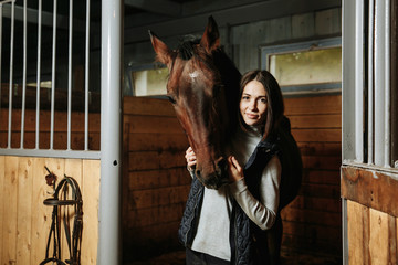 Portrait of smiling female jockey standing by horse in stable
