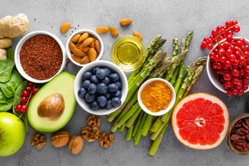 Healthy food background, spinach, quinoa, apple, blueberry, asparagus, turmeric, red currant, broccoli, mung bean, walnuts, grapefruit, ginger, avocado, almond, green peas and goji, top view