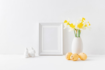 Home interior with easter decor. Mockup with a white frame and yellow daffodils in a vase on a light background