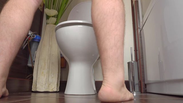 man pisses standing in the toilet in the bathroom.