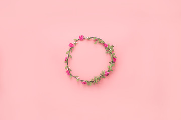 Wreath of flowers and leaves on a pink background. Flat lay, copy space, top view. Flowers composition.