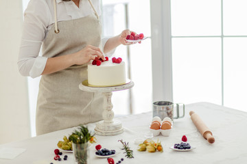 young girl using berries for decoration homemade cake, close up cropped photo, copy space