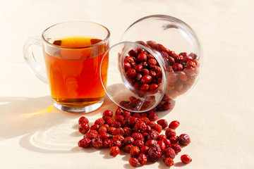 tea in a glass goblet and rose hips in a vase