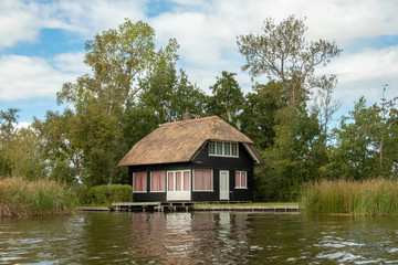 Giethoorn village with canals and rustic thatched roof houses in farm area.