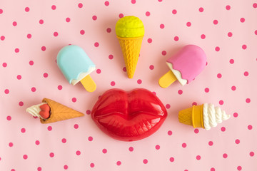 Flat lay of miniature ice cream and plastic lips isolated on pastel pink polka design background...
