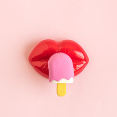 Flat lay of plastic lips and ice cream toy abstract on rose background.