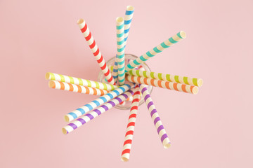 High angle view of paper straws in jar on rose background.