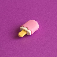 Miniature pink ice cream on purple background summer food and sweets abstract.