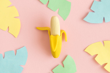 Small banana toy with multicolored origami leaves abstract on rose.