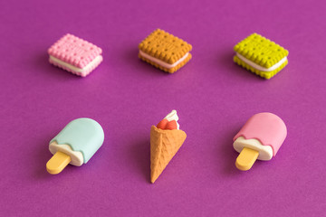 Small ice cream and biscuit toys isolated on purple abstract.