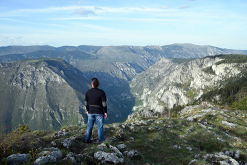 Young man stands in the edge of Tara Canyon and Tara River - Durmitor National Park. Near Zabljak, Montenegro.