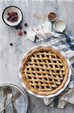 Overhead view of blueberry and raspberry pie on marble table
