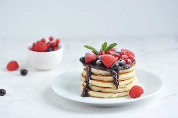 Pancakes with chocolate, juicy fruits and fresh mint leaves. White background. Close-up.