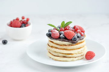 Pancakes with chocolate, juicy fruits and fresh mint leaves. The concept of a festive feast. White background. Close-up.