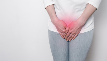A woman holds her hands for a sore crotch. Gynecological problems in the lower abdomen. Inflammation of the bladder.