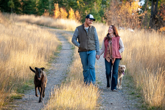 Couple hold hands and walk with dogs
