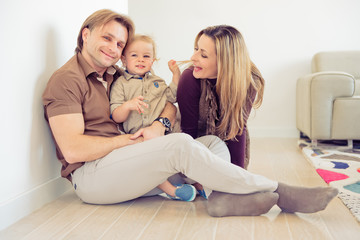 Fototapeta na wymiar Happy family sitting on floor with their little baby. Family spending time at home with their son.