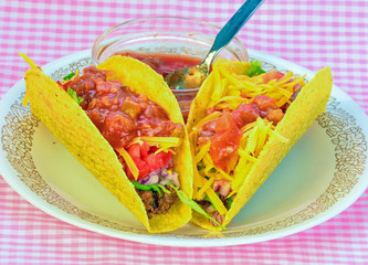 Two crispy tacos on cruncy corn tortillas with Salsa in Bowl