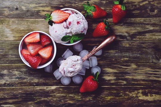 Two bowls of strawberry ice cream on the wooden background. Copy space and top view photo