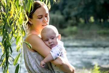 Happy mother with baby son standing in the park