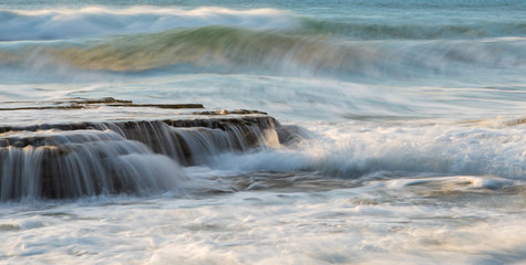 Rocky seashore with wavy ocean and waves crashing on the rocks