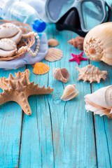 Diving mask with starfish and shells on old blue wooden background.