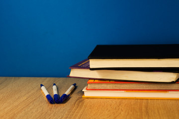 stack of books lying on top of each other wooden surface blue background 3 white handles
