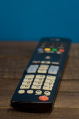 TV remote on a wooden lining and blue background