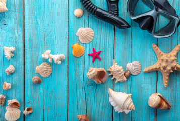 Diving mask with starfish and shells on old blue wooden background. Top view. Flat lay.