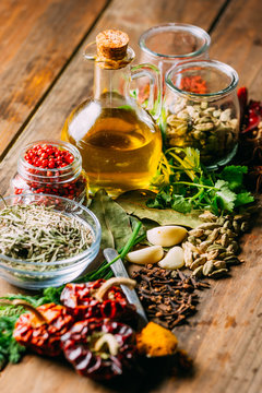 Assorted spices and herbs and bottle of oil placed on wooden tabletop