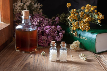 Two bottles of homeopathic pills with dried herbs and materia medica