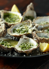 Grilled oysters with Parsley and garlic butter served with parmesan and lemon wedges