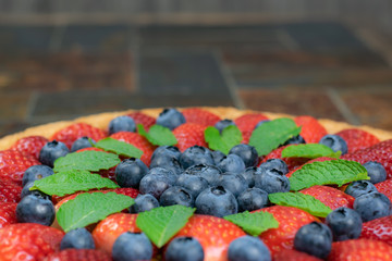 Homemade cake with strawberries and blueberries on a stone table.Tasty dessert.
