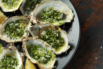 Grilled oysters with Parsley and garlic butter served with parmesan and lemon wedges