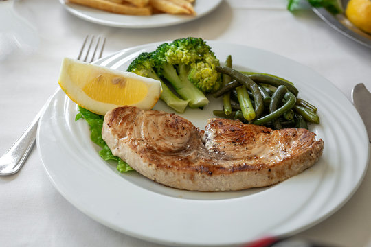 Restaurant table ready to eat. Cutlery, napkins, cups; dishes. swordfish
